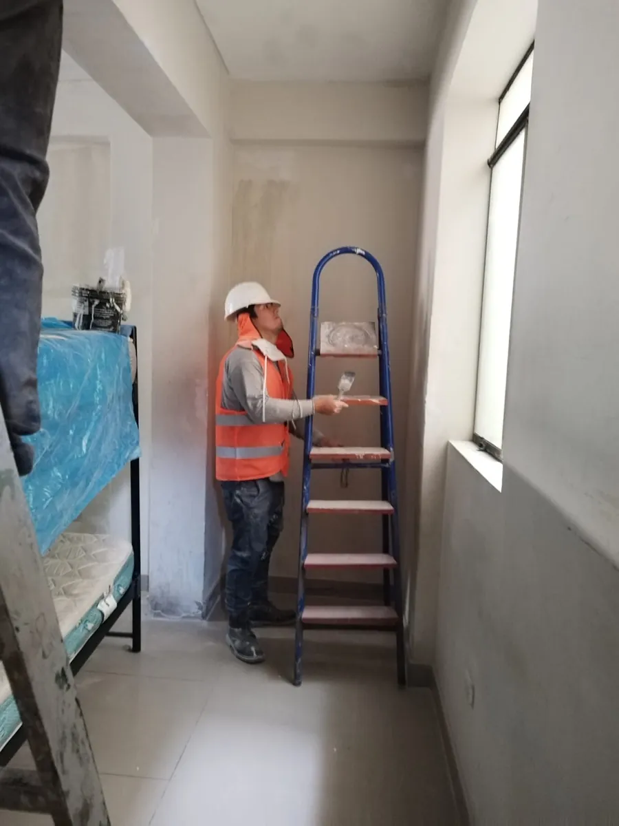 Trabajador pintando pasillo interior